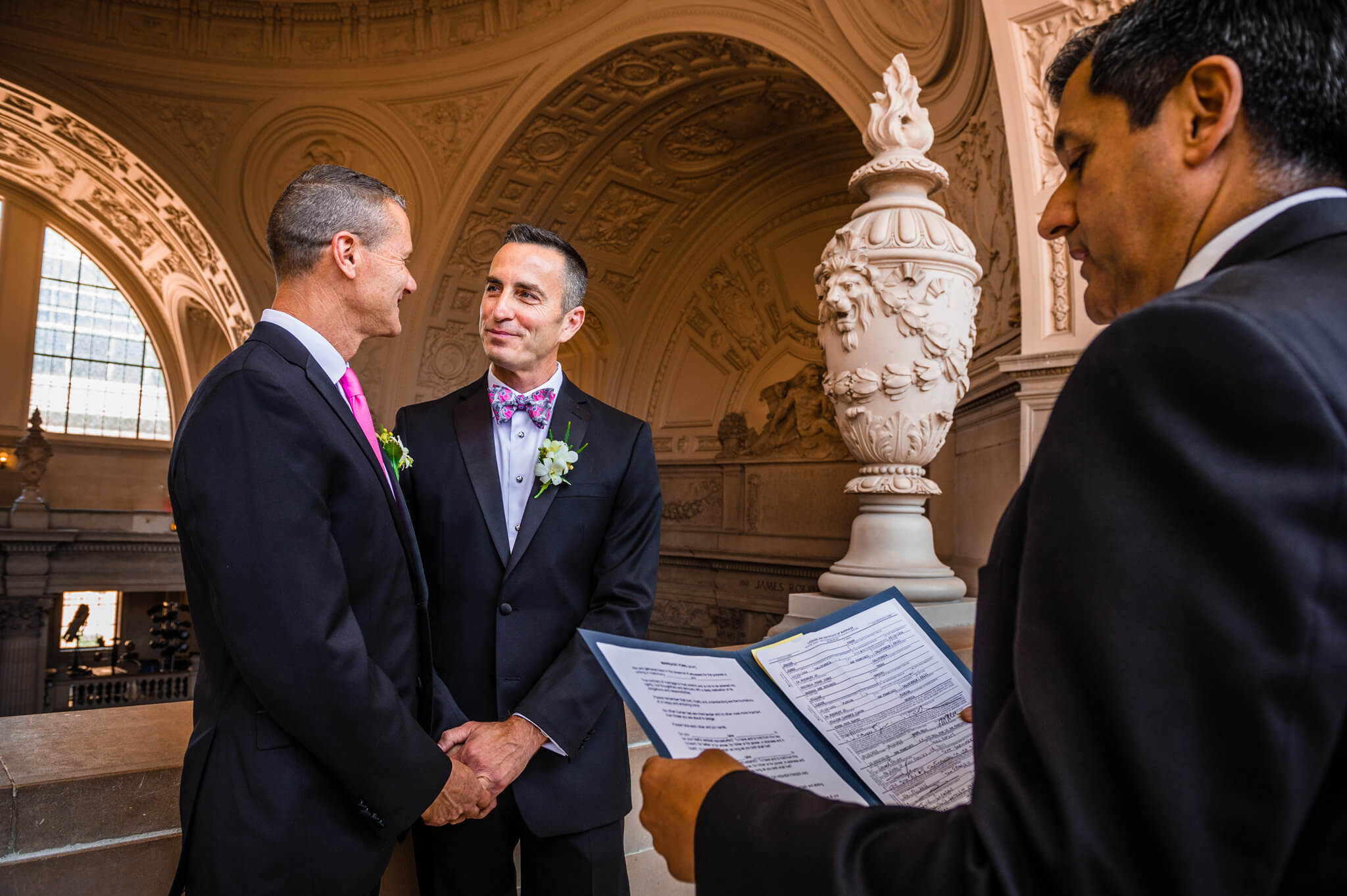 Two men stand together at the altar as wedding is officiated at San Francisco City Hall