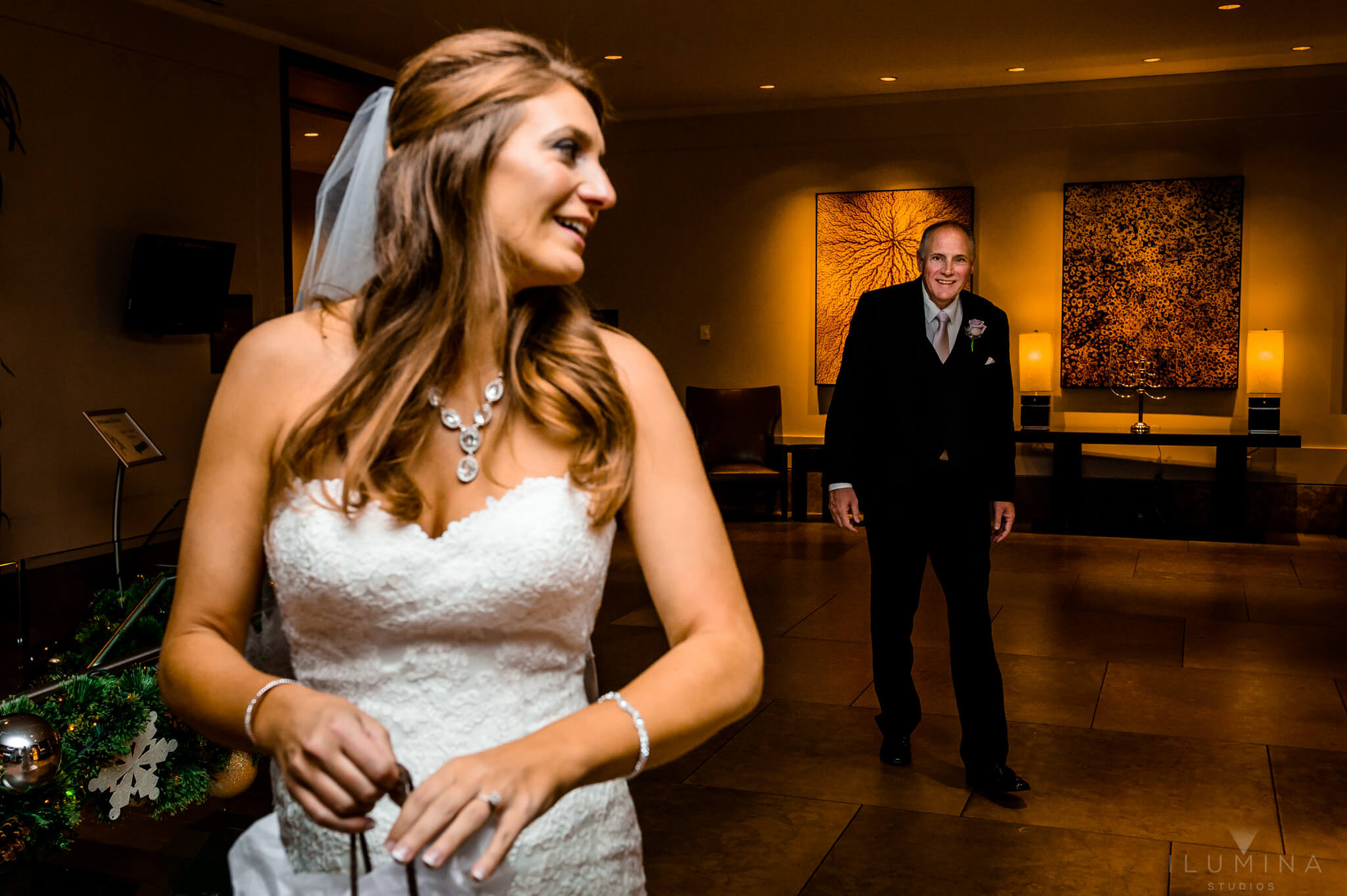 Color photo of bride in foreground looking back at happy elderly man in background