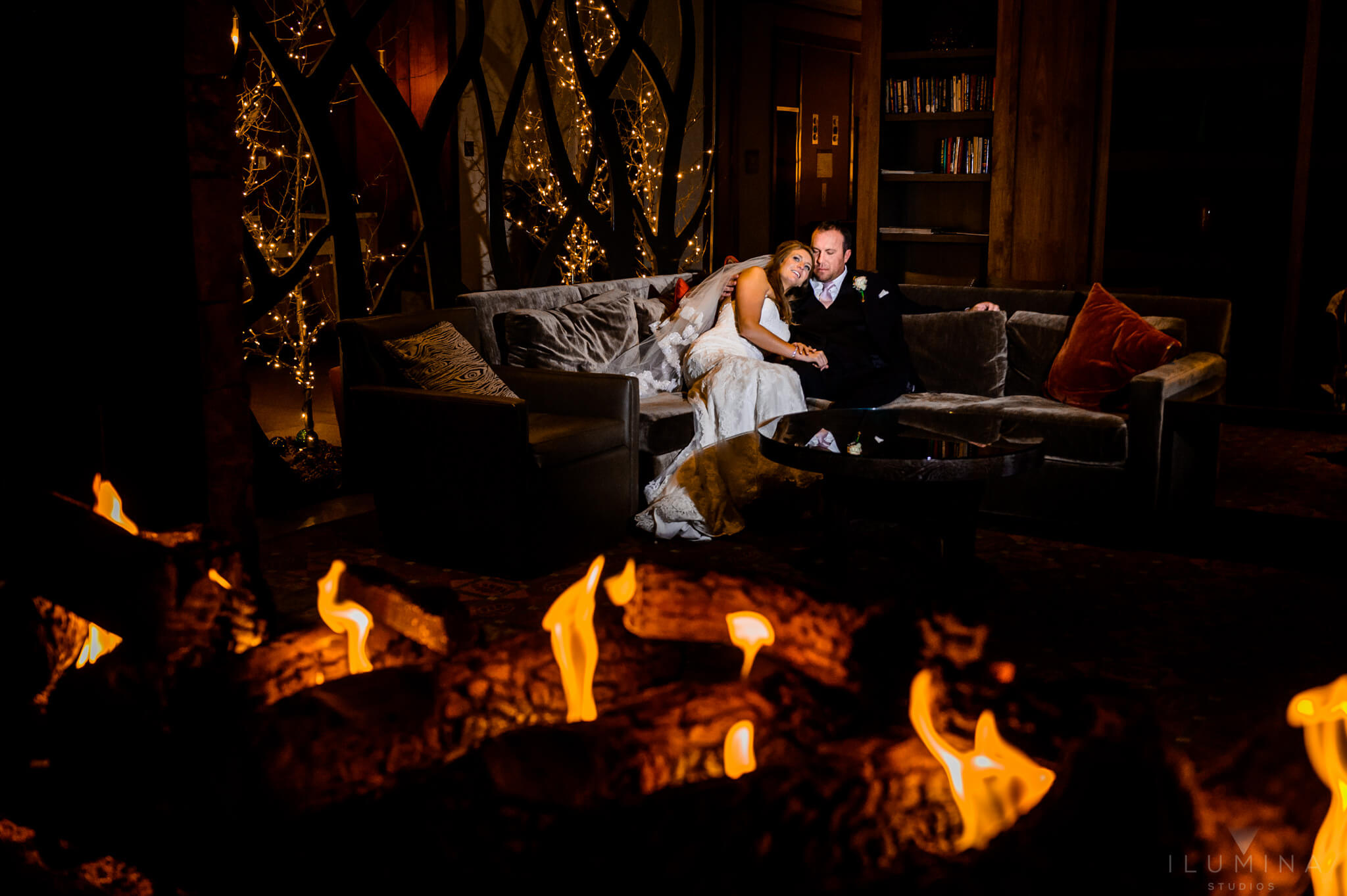 Color photo of bride and groom cuddling by fire in a lodge in Vail, Colorado