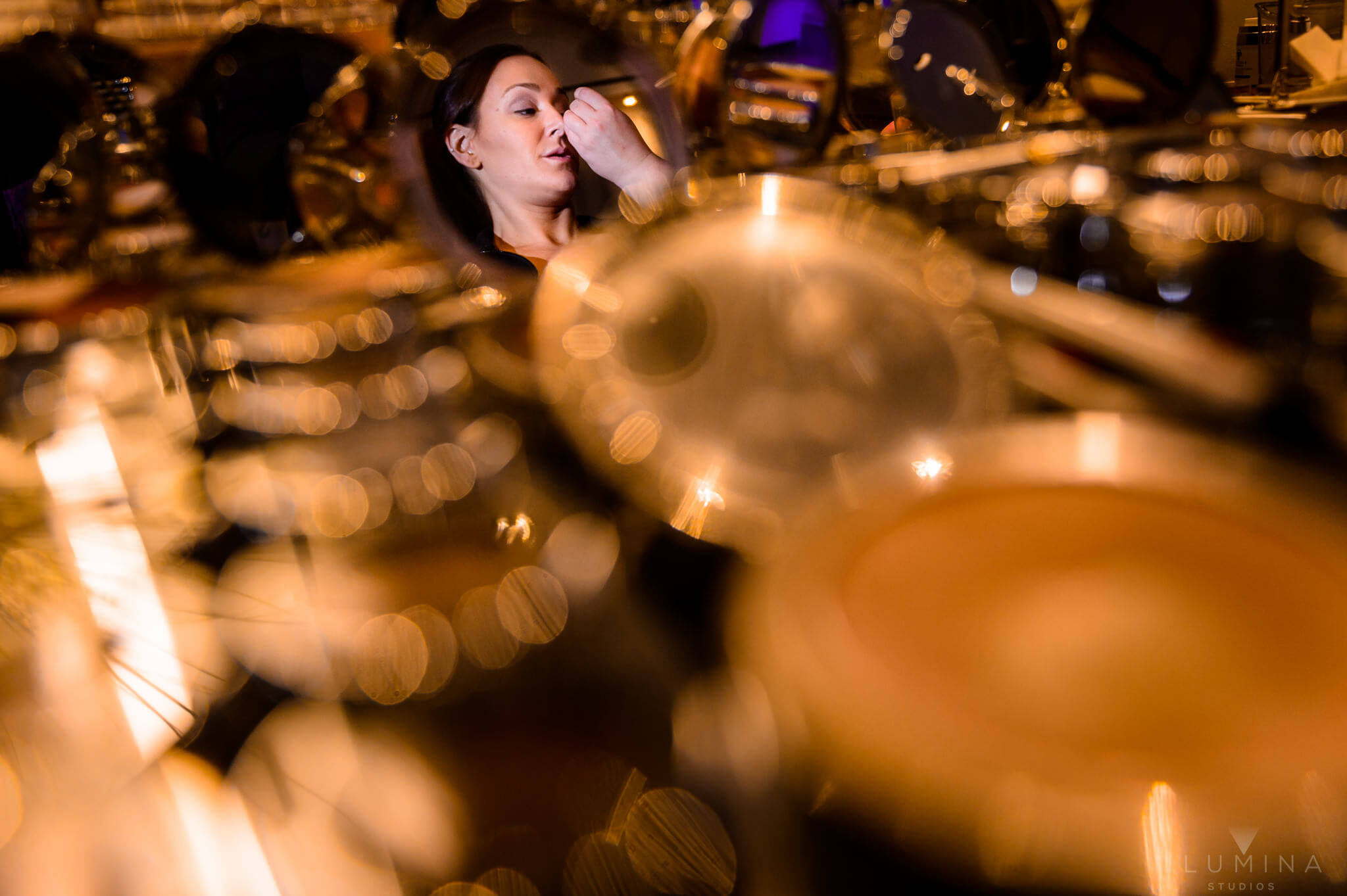 Creative color photo of woman applying makeup with blurry gold in foreground
