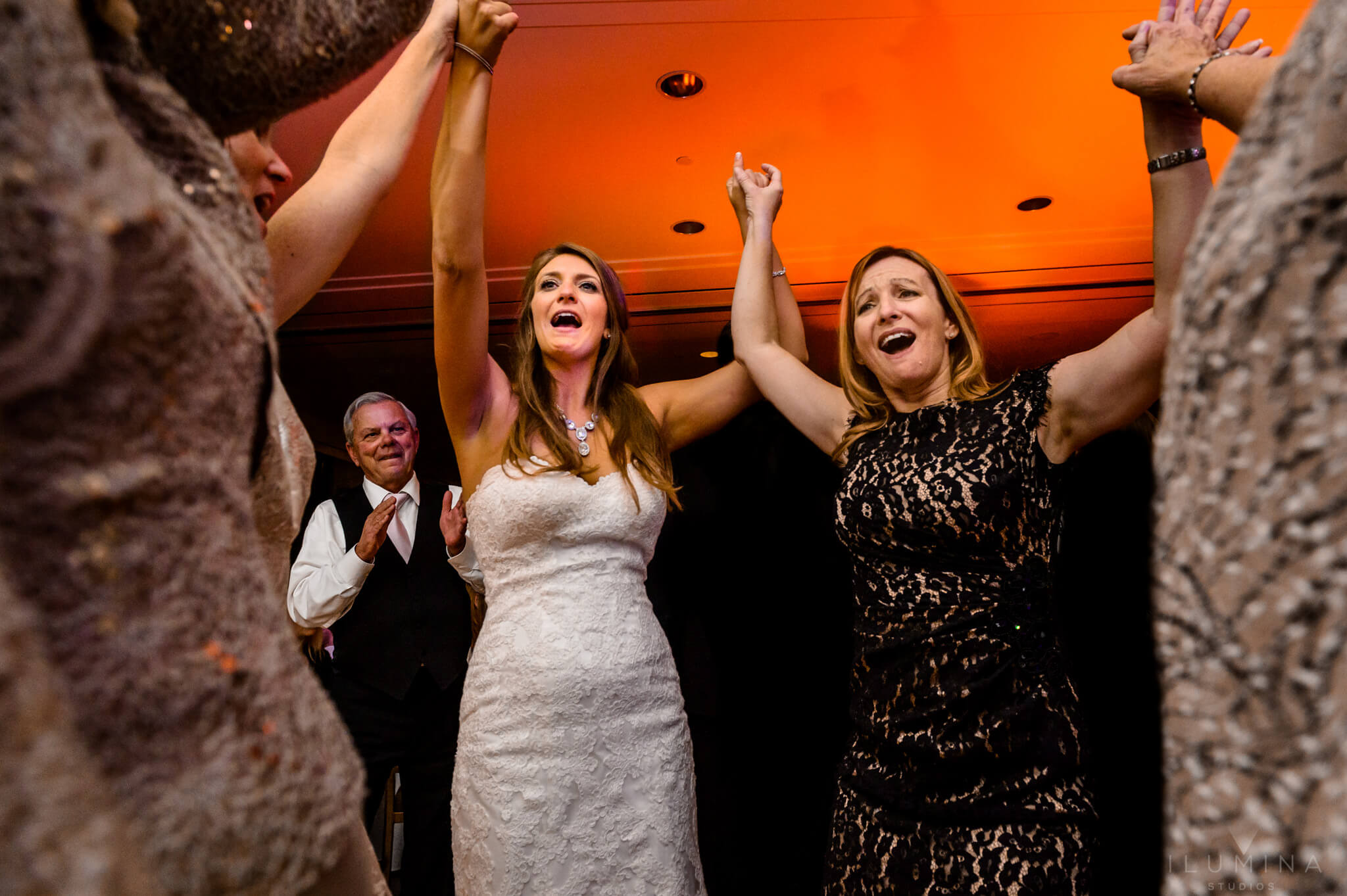 Color photo of bride holding hands and singing with friends on dance floor at Vail, Colorado wedding