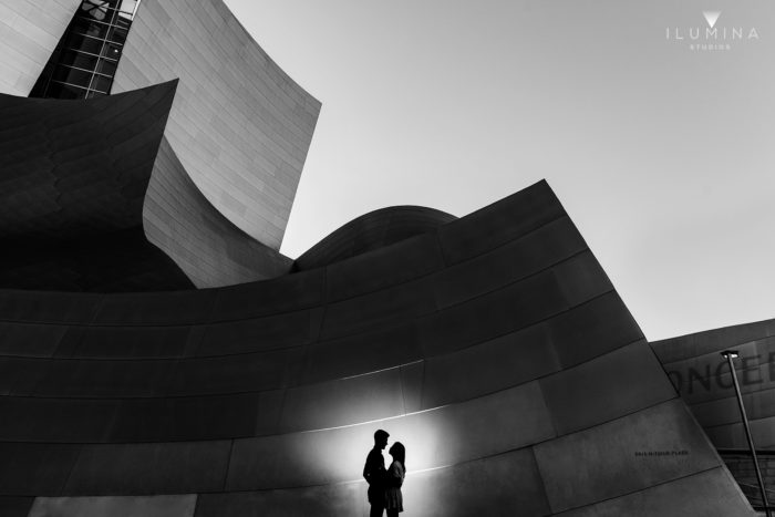 Black and white silhouette engagement photo of man and woman leaning for kiss in front of Walt Disney Concert Hall in Los Angeles, California