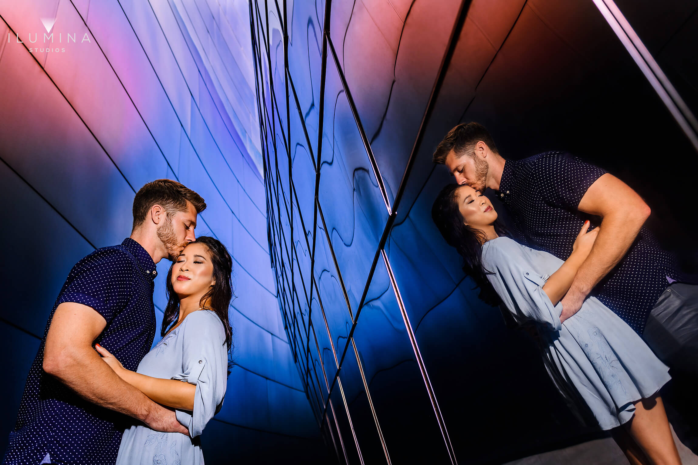 Vivid engagement photo of man kissing woman's temple next to reflection at Walt Disney Hall in Los Angeles, California