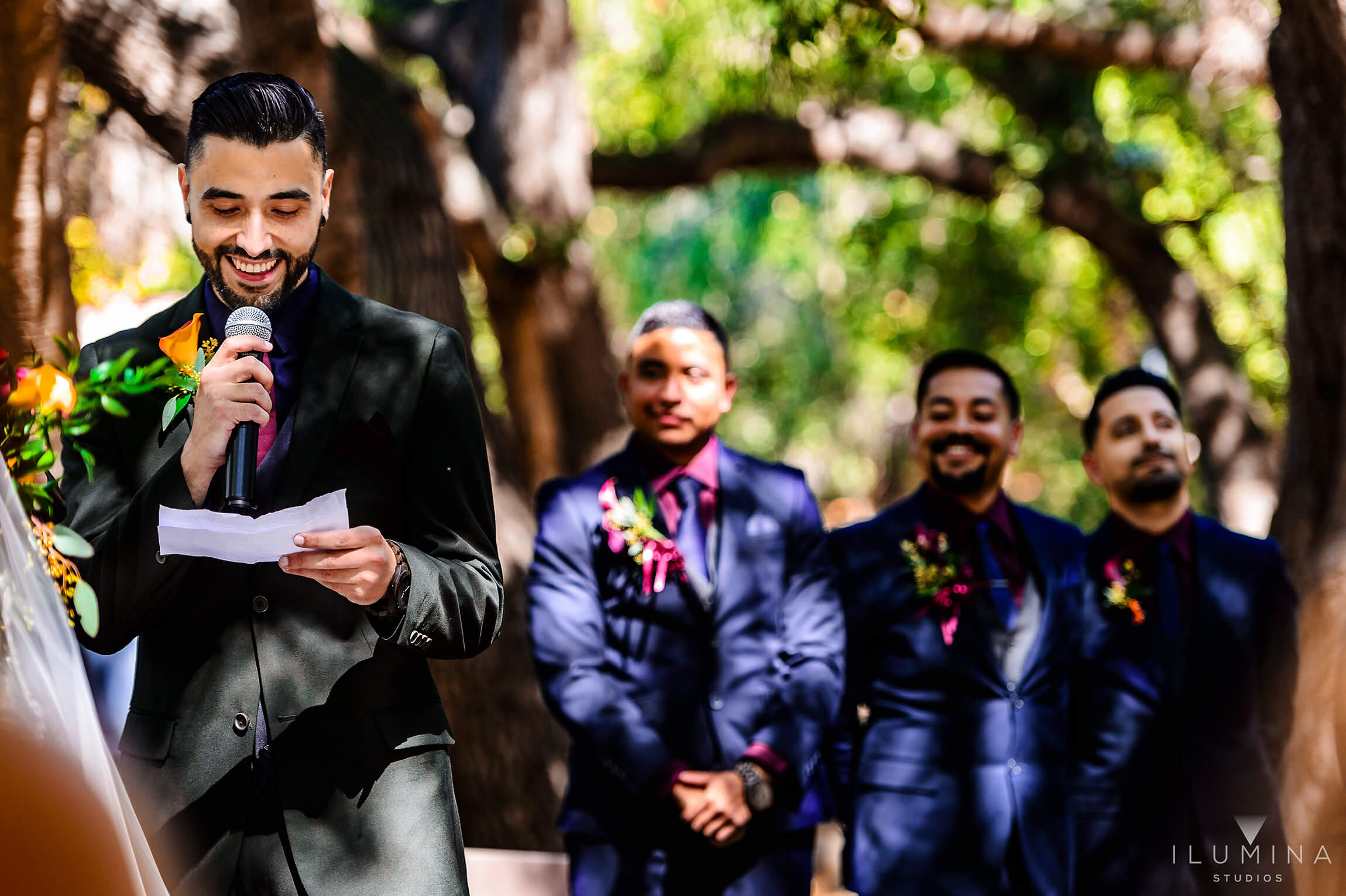 Color photo of groom reading vows to bride with groomsmen in background at Anaheim Oak Canyon Nature Center wedding
