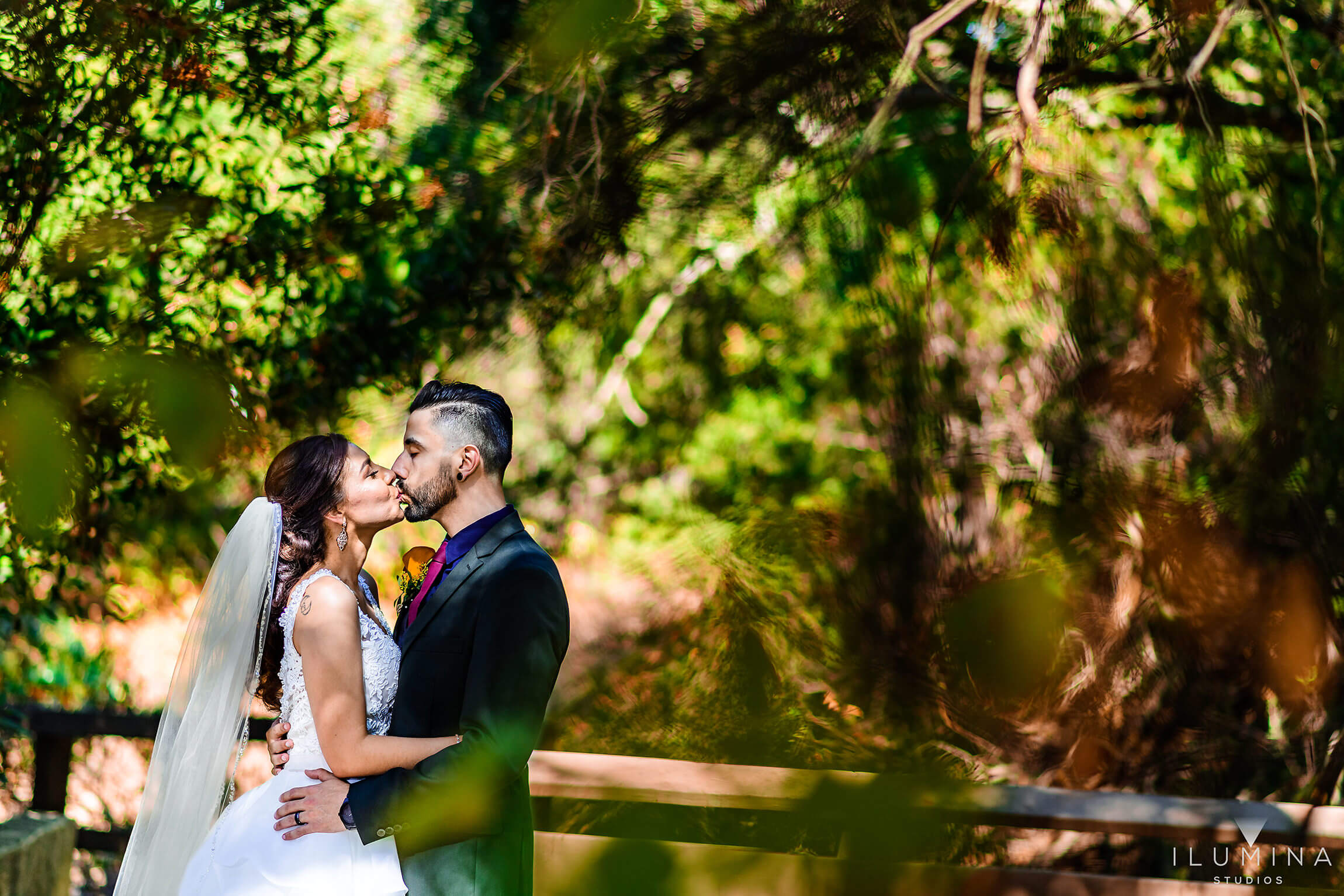 Bride and groom kiss each other in the forest of Anaheim Oak Canyon Nature Center after wedding