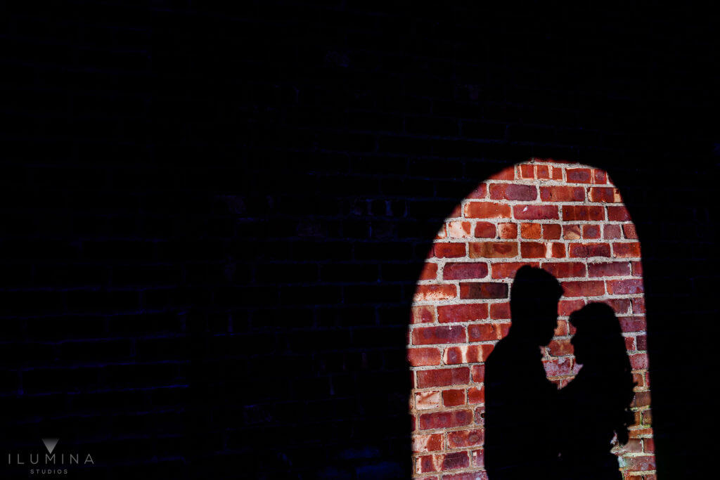 Silhouette of hugging man and woman on red brick wall surrounded by shadows in Brooklyn, New York City