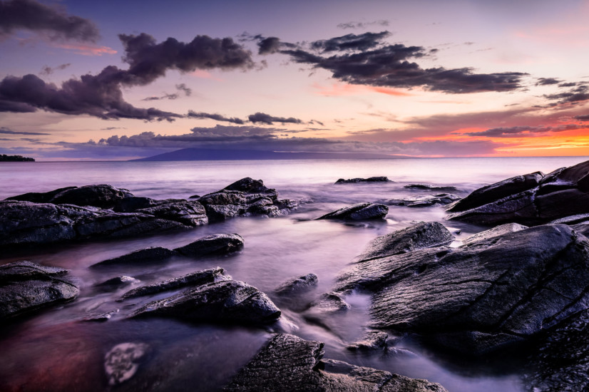 Foggy rocks near the water and a purple sunset sky