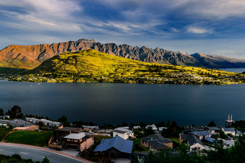 Rolling green hills in the background, river of blue water and a cliffside full of houses in front