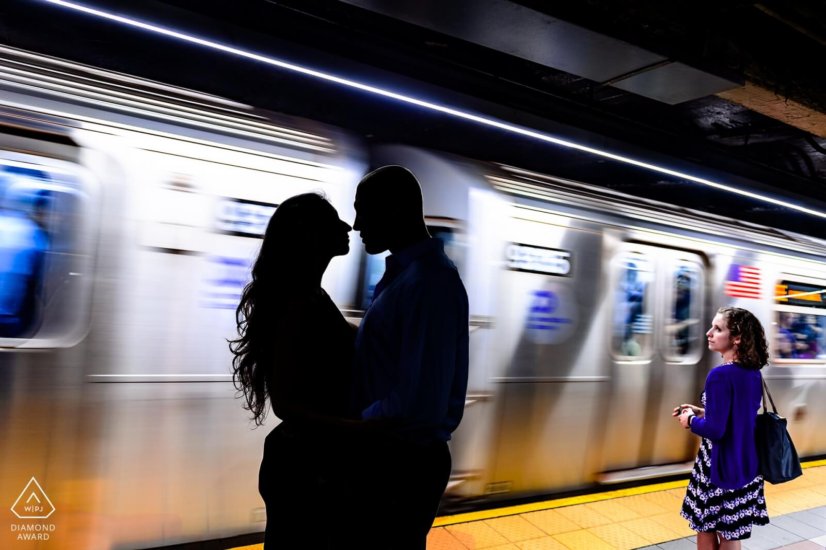 silhouette of man and woman holding eachother in front of a moving subway train as a stranger looks