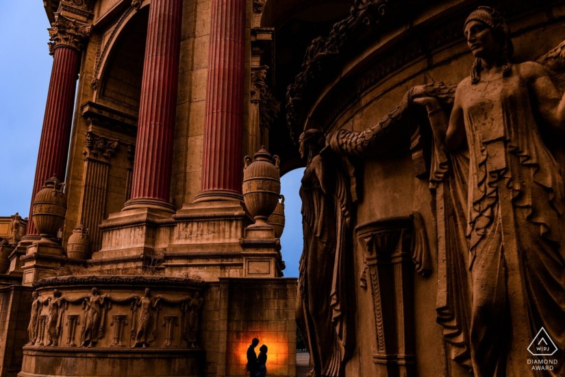 man and woman silhouette next to a large historic building with statues